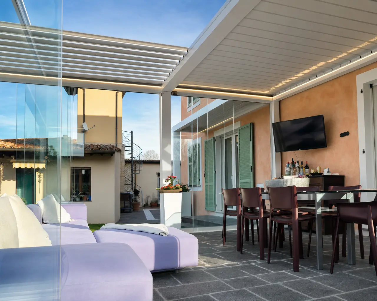 Pergola bioclimatica su una terrazza con divano e tavolo da pranzo