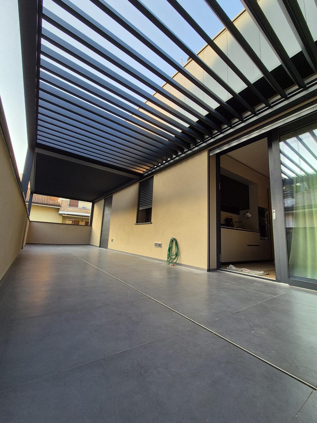 Pergola bioclimatica a lamelle orientabili color antracite su un terrazzo